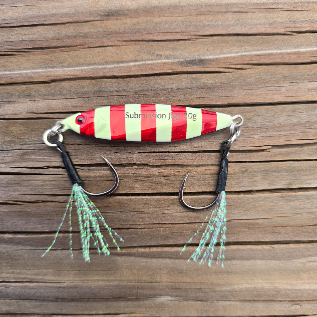 Red and glow striped fishing lure on a wooden surface
