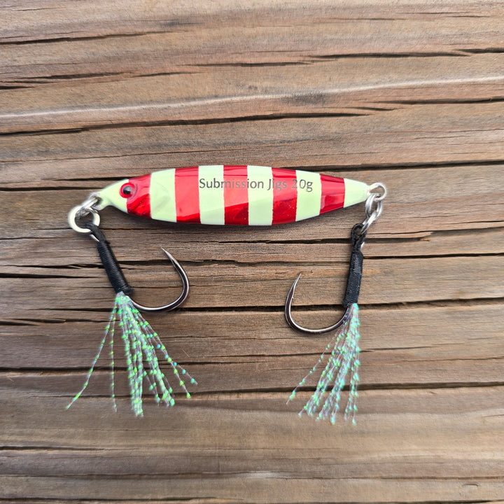 Red and glow striped fishing lure on a wooden surface