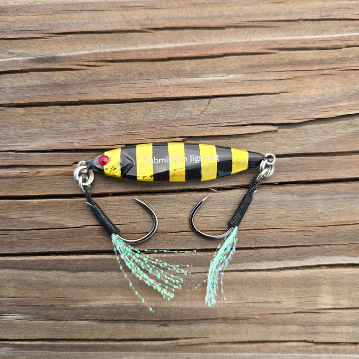 Fishing lure with black and yellow striped body on a wooden surface