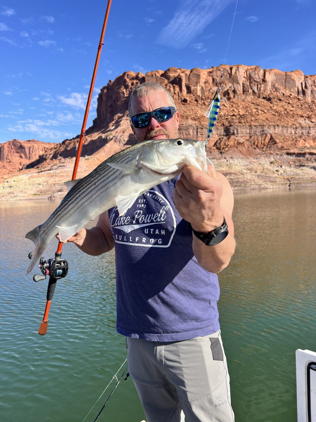Angler holding a striped bass caught with a slow pitch fishing jig