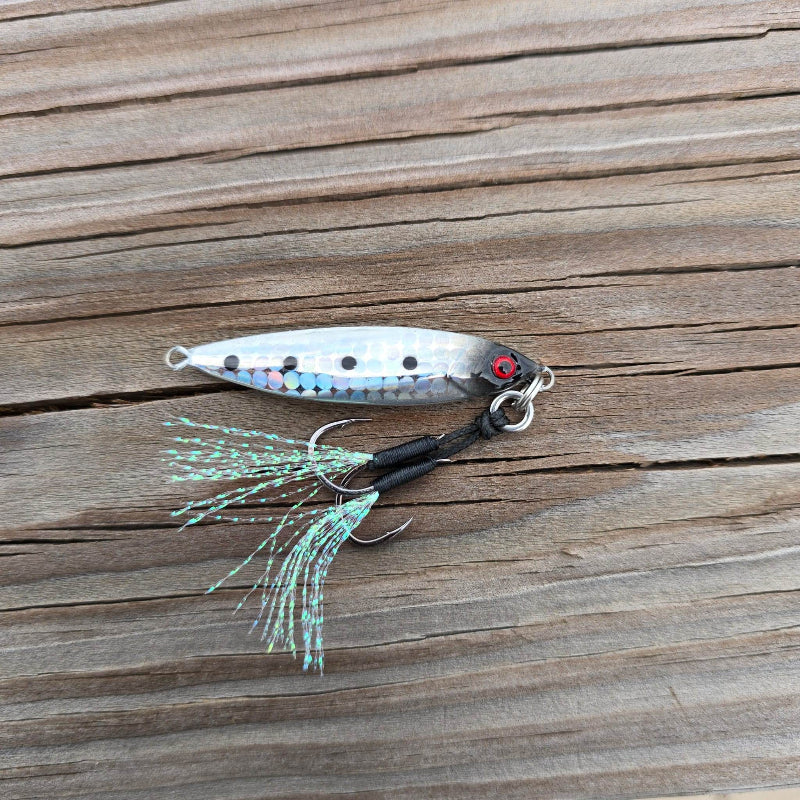 Side view of the Submission Fishing Micro Mercenary 15g slow pitch jig in Stellar Shad color with reflective foil finish, BKK assist hooks, and UV flash tassels.