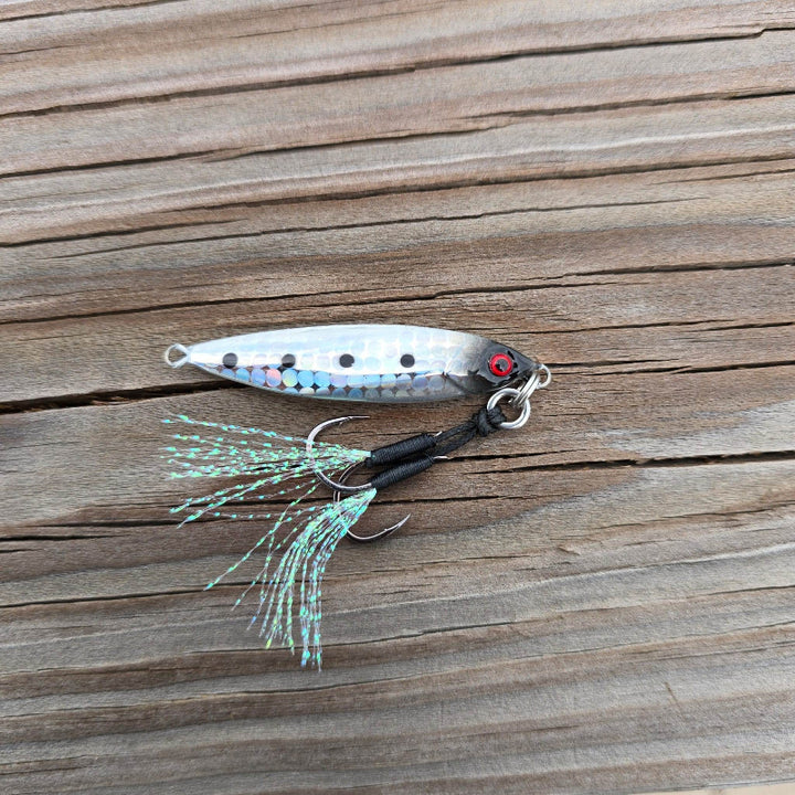 Side view of the Submission Fishing Micro Mercenary 15g slow pitch jig in Stellar Shad color with reflective foil finish, BKK assist hooks, and UV flash tassels.