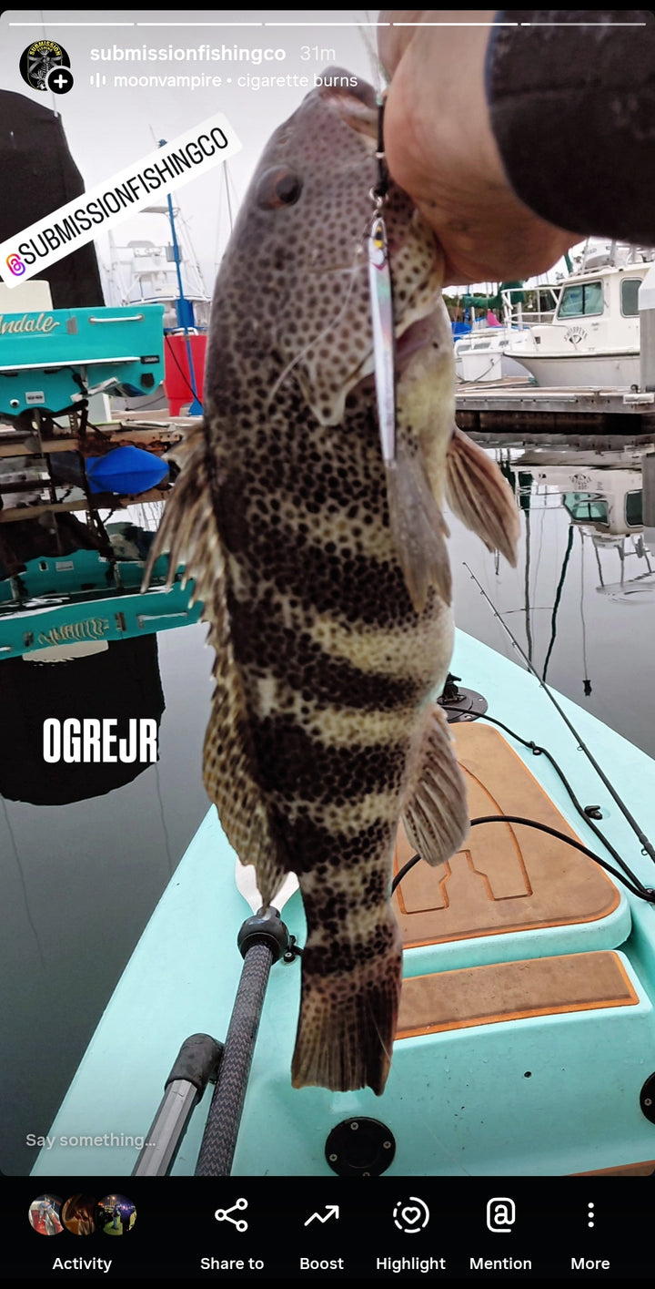 Instagram Story showing a spotted bay bass caught on a Submission Fishing slow pitch jig from a kayak near a marina.